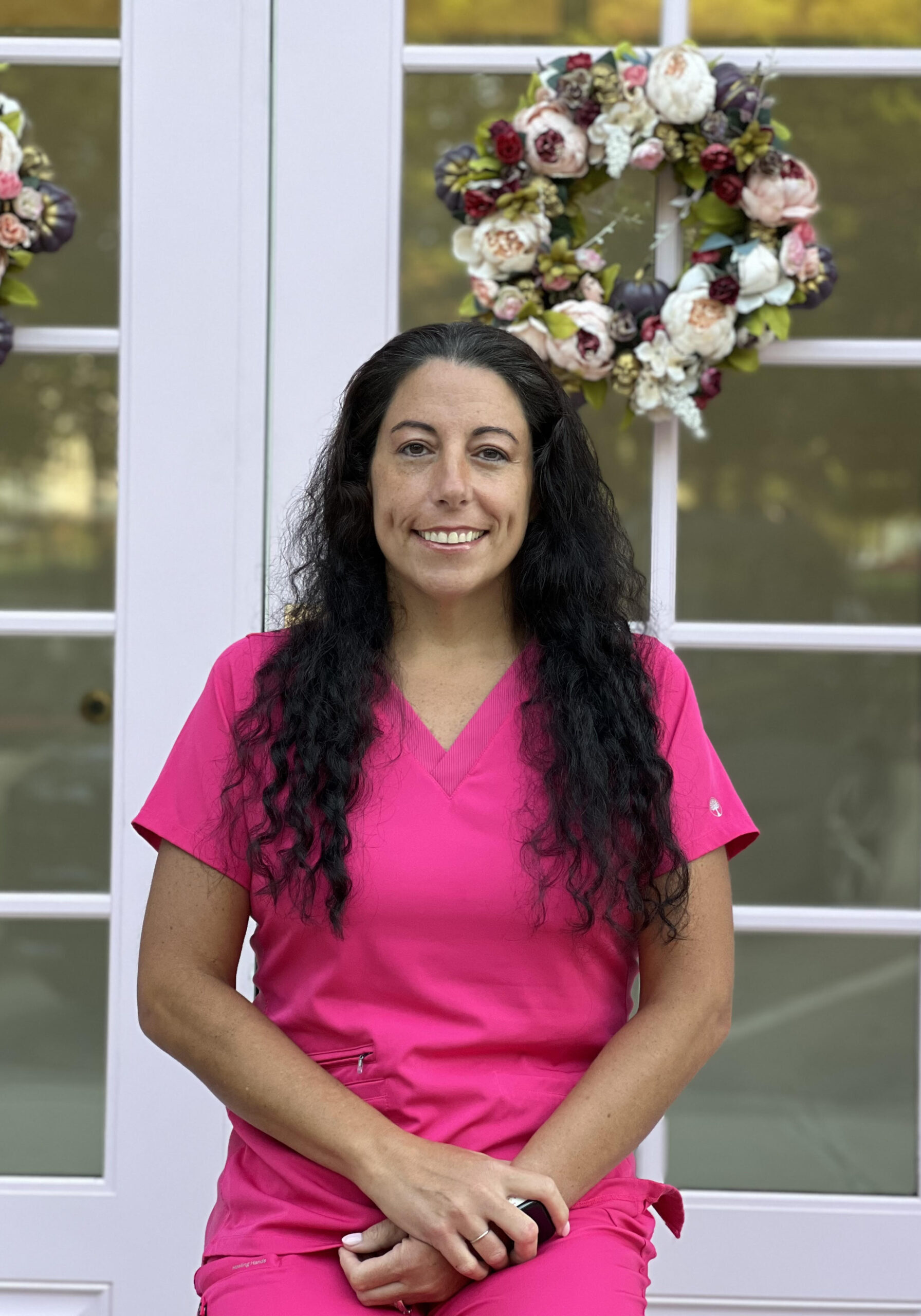 A woman in pink scrubs standing outside of a building.